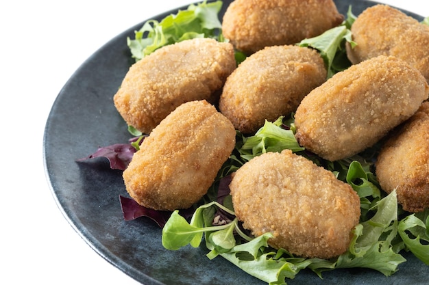 Een bord gebakken kipnuggets op een bedje van sla