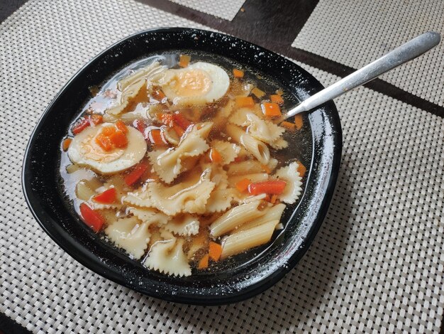 Een bord groentesoep met vlinders pasta op de keukentafel