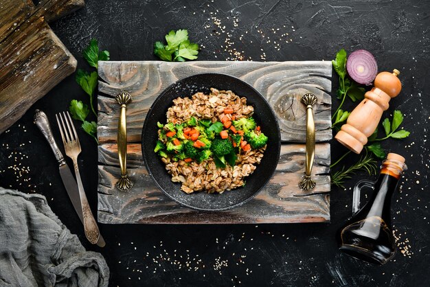 Een bord met gezond voedsel Havermout met broccoli, wortelen en peterselie Bovenaanzicht Op een zwarte achtergrond Gratis kopieerruimte