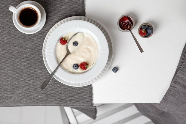 Een bord met griesmeelpap en bosbessen en frambozen op een witte tafel en een grijs servet met koffie. bovenaanzicht. Hoge kwaliteit foto