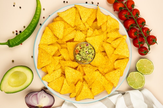 Een bord met nacho's maïschips met guacamole en ingrediënten rode ui avoca pepers en tomaten