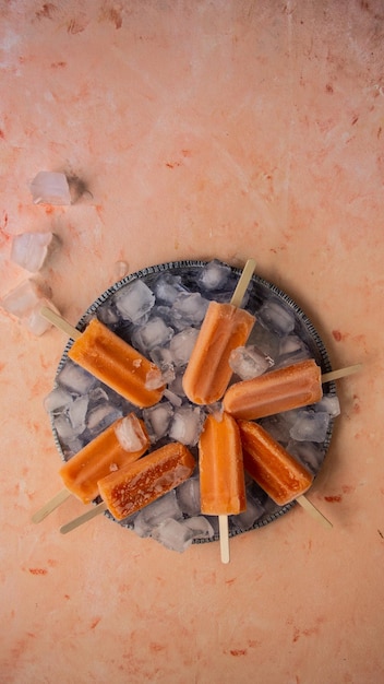 Foto een bord met oranje ijslolly's met ijs op een roze achtergrond