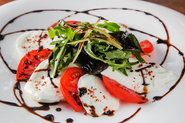 Een bord mozzarella, tomaat en rucola salade.