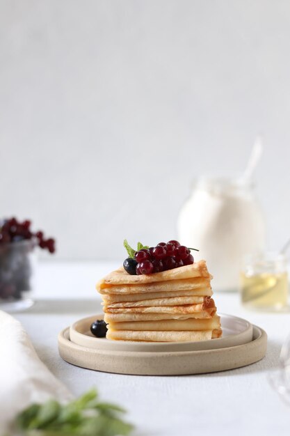 Een bord pannenkoeken met daarop bosbessen en druiven