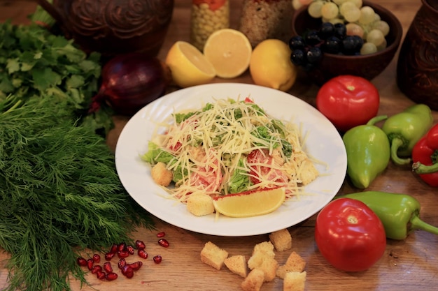 Een bord salade met citroenen en tomaten op een tafel met andere etenswaren.