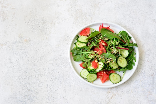 een bord salade met komkommer tomaten arugula en zaden erop kopieer ruimte