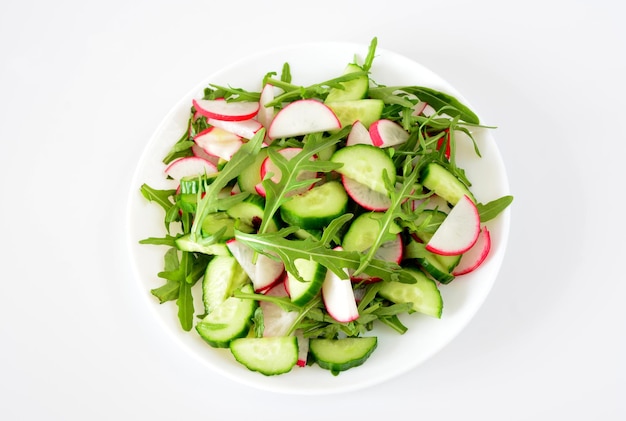 Foto een bord salade met radijs, komkommer en arugula geïsoleerd op wit