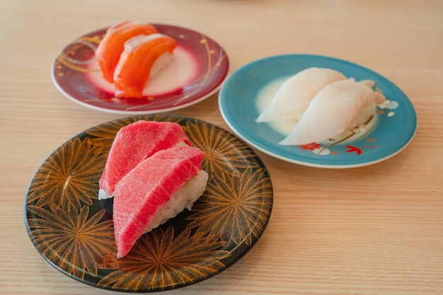 Een bord sushi staat op een tafel met twee borden sushi.