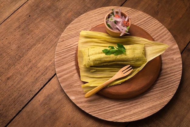 Foto een bord tamales met een kom koriander en een vork.