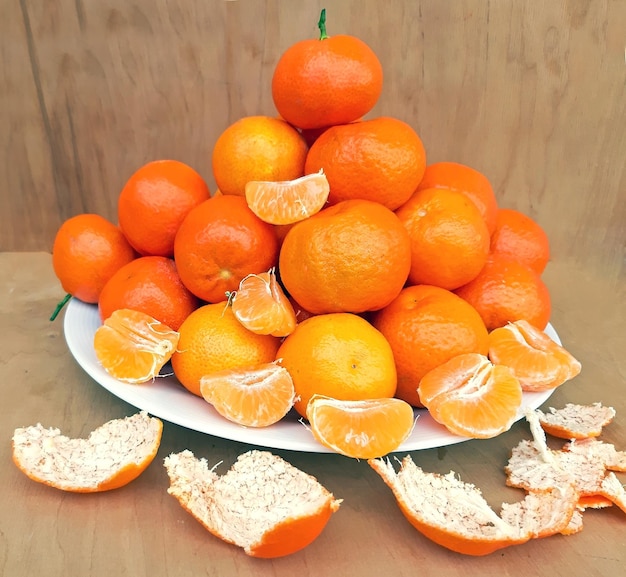 Een bord vol clementines op een houten ondergrond