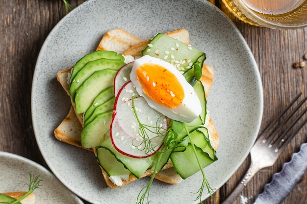 Een bordje toast met daarop een gebakken ei en komkommer.