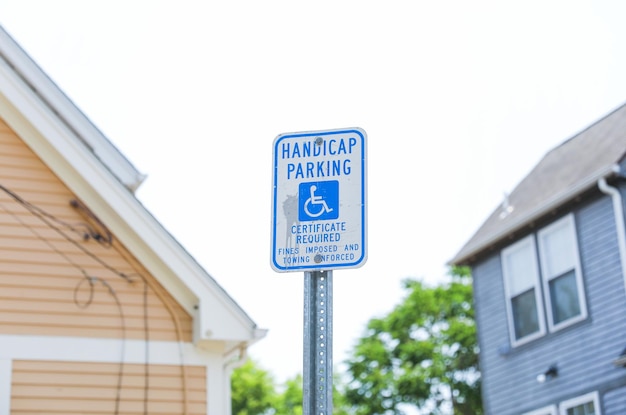 Een bordje voor een parkeerplaats voor gehandicapten staat voor een huis.