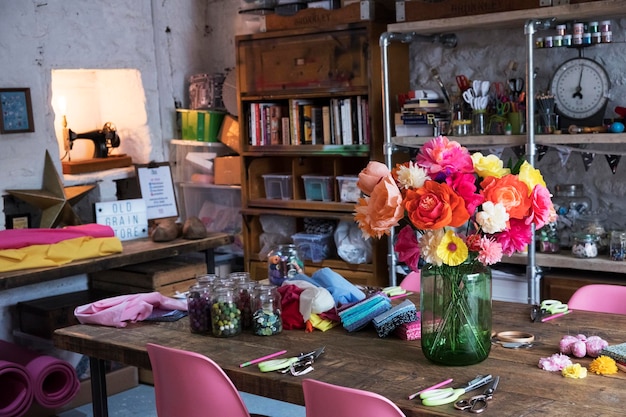 Een bos kleurrijke handgemaakte stoffen bloemen in een vaas op een tafel in een werkplaats