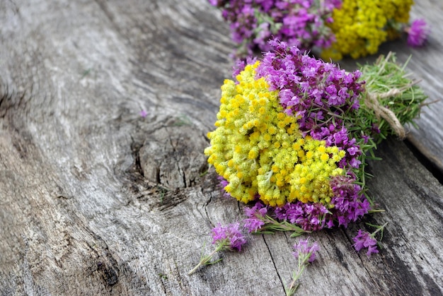 een bos paarse en gele bloemen op een houten tafel.