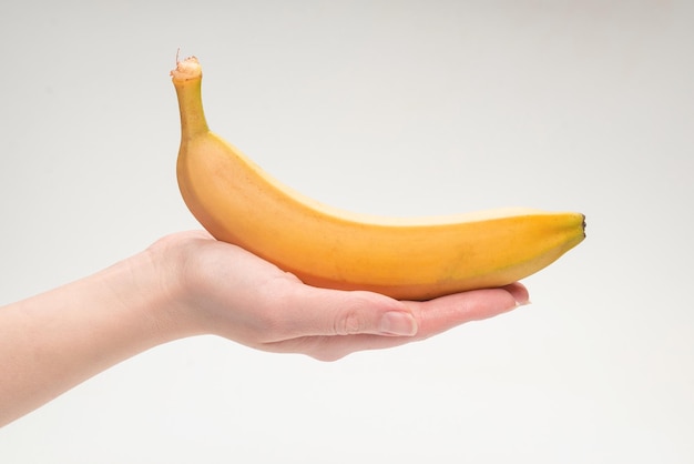 Een bos van bananen in vrouwenhand die op witte achtergrond wordt geïsoleerd