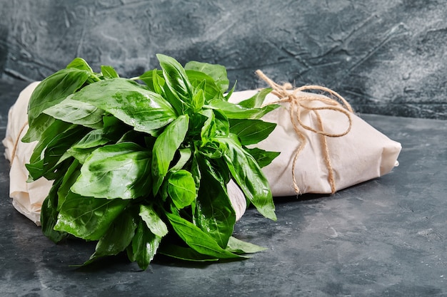 Een bosje verse groene basilicum, op een grijze tafel, eco-verpakking, voedselbezorging, milieuproblemen.