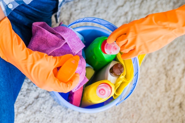 Foto een bovenaanzicht van een persoon die een spray fles uit blauwe emmer