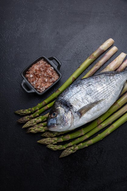 Een brasemvis op een zwarte achtergrond met asperges