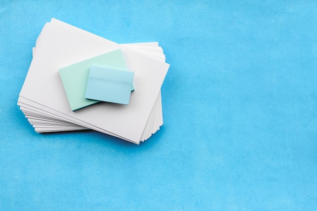 Een briefpapierlay-out op een blauwe achtergrond, een stapel blanco witte kaartenstickers en een wekker