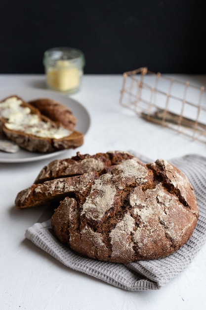 Een brood van roggebrood en een sandwich met boter op een zwarte achtergrond.