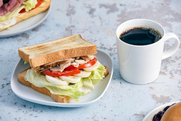 Een broodje kip erop naast een kop koffie.