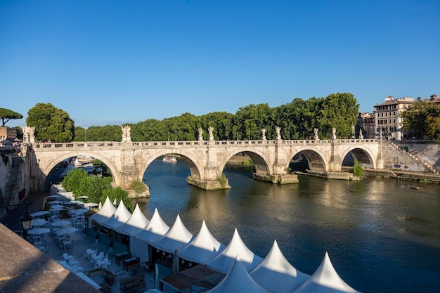 Een brug met sculpturen over een rivier in Rome met uitzicht op de oude stad