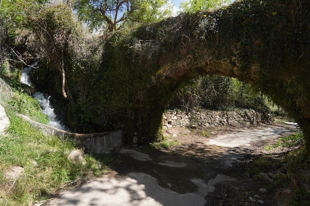 Een brug over een rivier met op de achtergrond een waterval