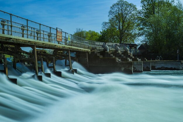 Foto een brug over water tegen een blauwe hemel.