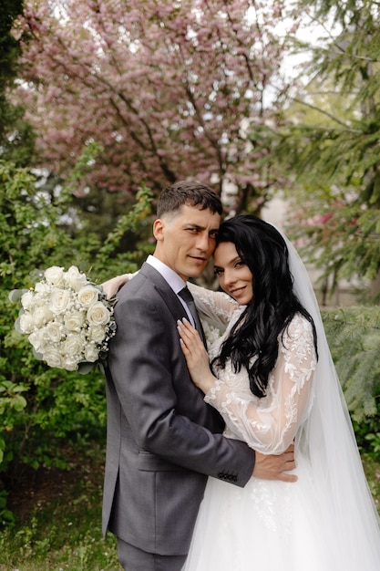 Een bruid en bruidegom poseren voor een foto in een tuin.