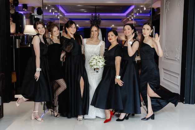 een bruid en haar bruidsmeisjes poseren voor een foto in zwarte jurken