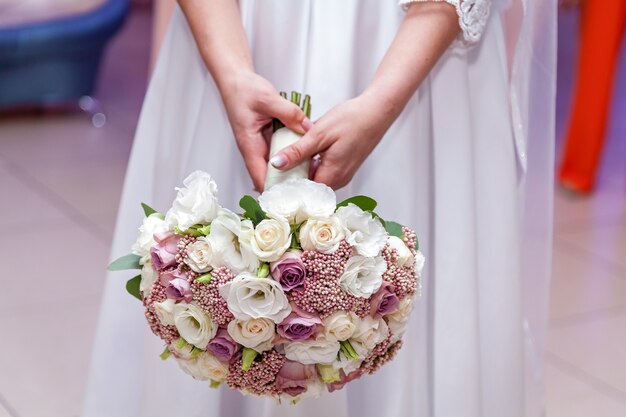 Een bruid houdt een huwelijksboeket met rozen in handen.