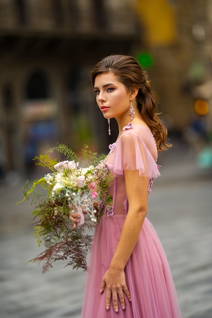 Een bruid in een roze jurk met een boeket staat in het centrum van de oude stad van Florence in Italië.