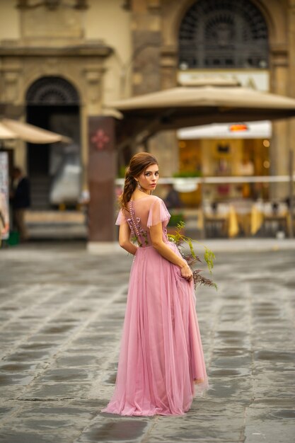 Een bruid in een roze jurk met een boeket staat in het centrum van de oude stad van florence in italië.