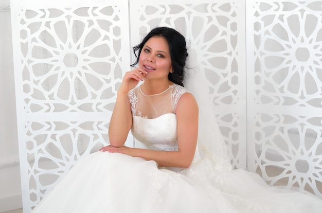 Een bruid in een witte trouwjurk in een lichte kamer