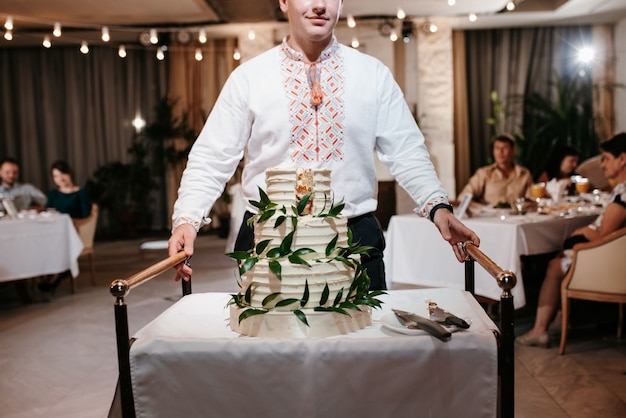 Een bruidstaart in verschillende lagen op tafel wordt gedragen door een ober