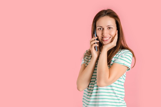 Een brunette meisje praat met haar vriend die op een roze achtergrond staat. Ruimte kopiëren
