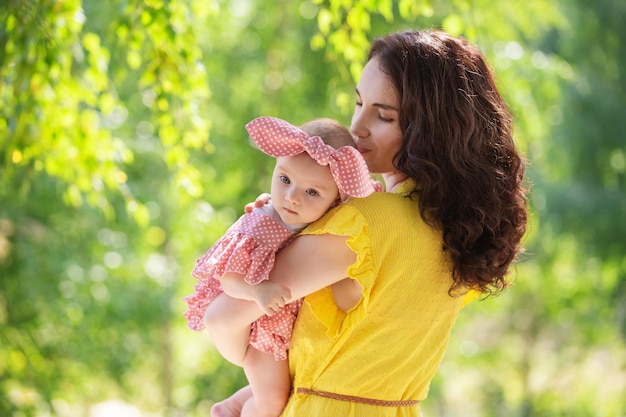 Een brunette vrouw een jonge moeder met een babymeisje wandelen in het park