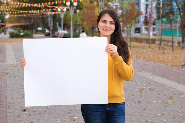 Een brunette vrouw lacht en houdt een leeg wit laken vast