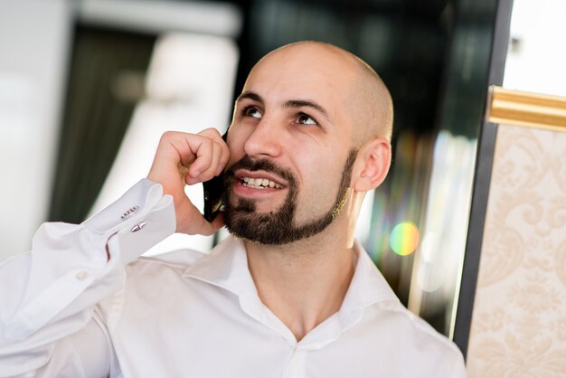 Een brute kale man praten aan de telefoon.