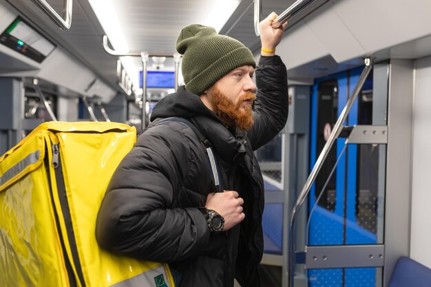 Foto een brute pizzabezorger gaat met een gele tas naar de metro
