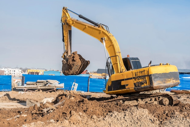 Een bulldozer van een graafmachine die grond graaft en de bouwplaats aan het scheppen is