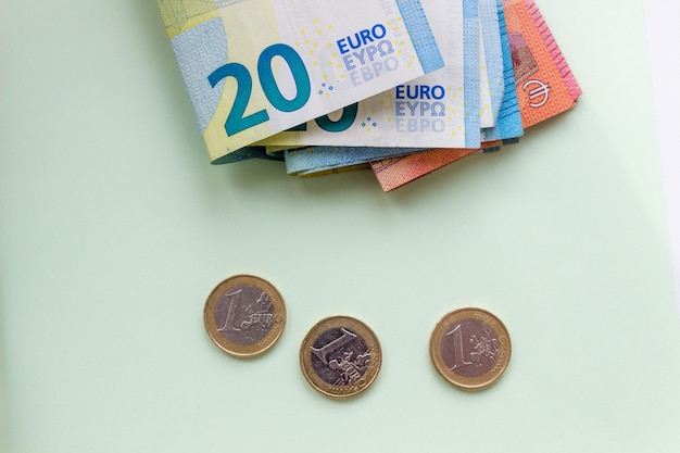 Een bundel van 20 eurobankbiljetten en -munten op een lichte ondergrond