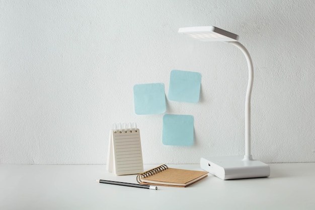 een bureaulamp met notitiepapier erop en een pen op de tafel