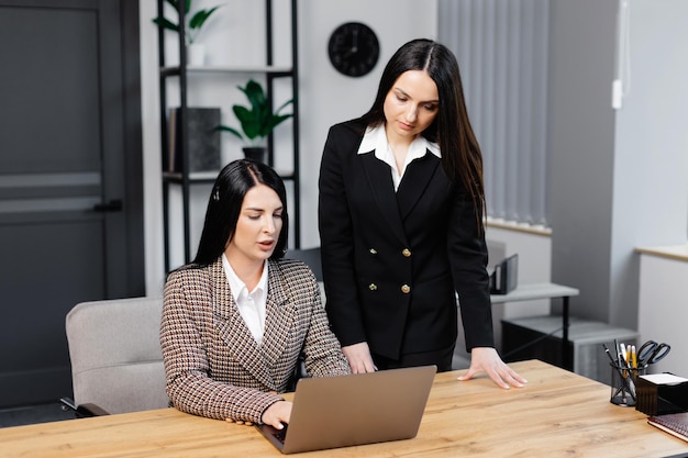 Een callcenteragent met een headset werkt aan een hotline in een modern kantoor. Twee aantrekkelijke jonge vrouwen werken in het kantoor.