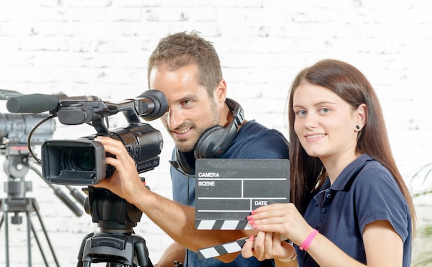 Een cameraman en een jonge vrouw met een filmcamera en klepel