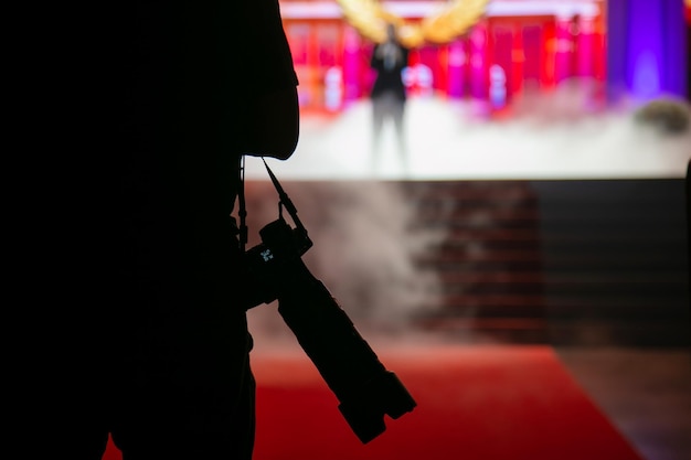 Foto een cameraman met een zwarte camera staat voor het podium waar een man in een concert zingt