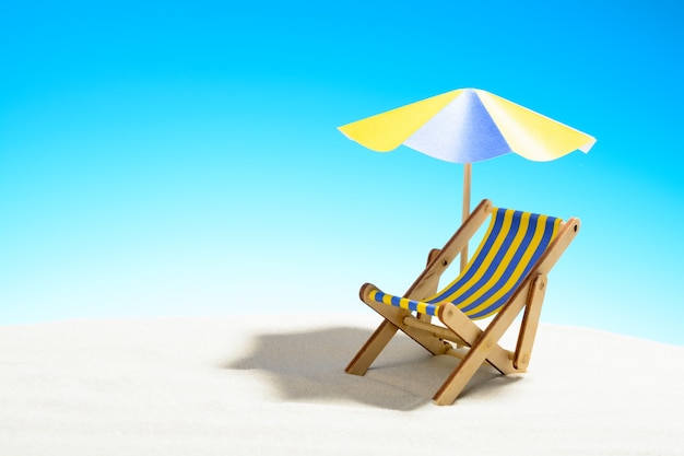 Een chaise longue onder een parasol op het zandstrand met kopieerruimte