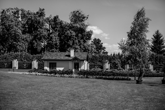 Een charmant speelhuisje ligt aan de rand van een schaduwrijke meerjarige tuin. zwart-wit foto