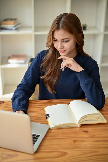 Een charmante Aziatische studente werkt aan haar opdrachten op haar laptop