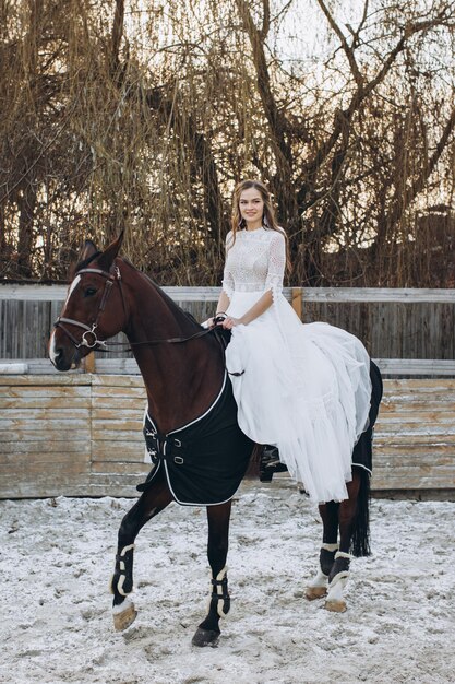 Een charmante bruid berijdt een paard op een ranch in de winter